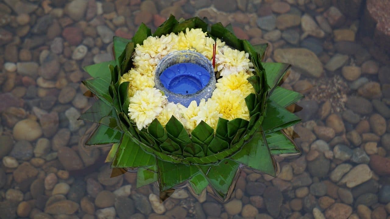 A krathong made of banana leaves and flowers, with a candle at its centre