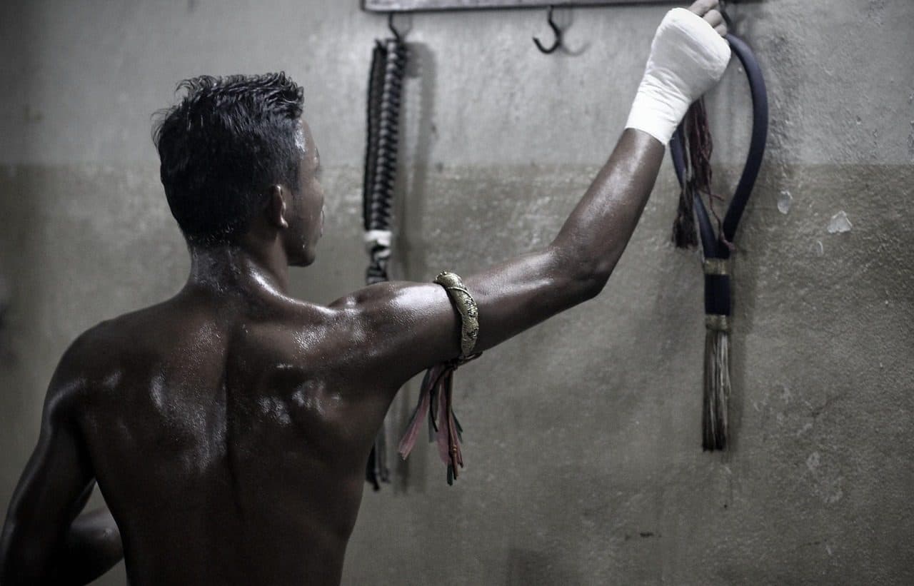 A Muay Thai boxer training in a gym, seen from behind