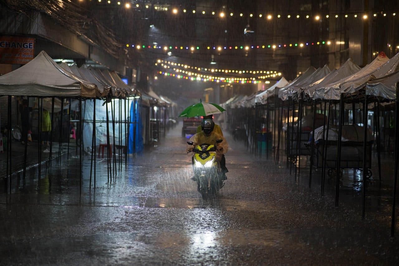 A night market street in Bangkok in heavy rain, lit by string lights