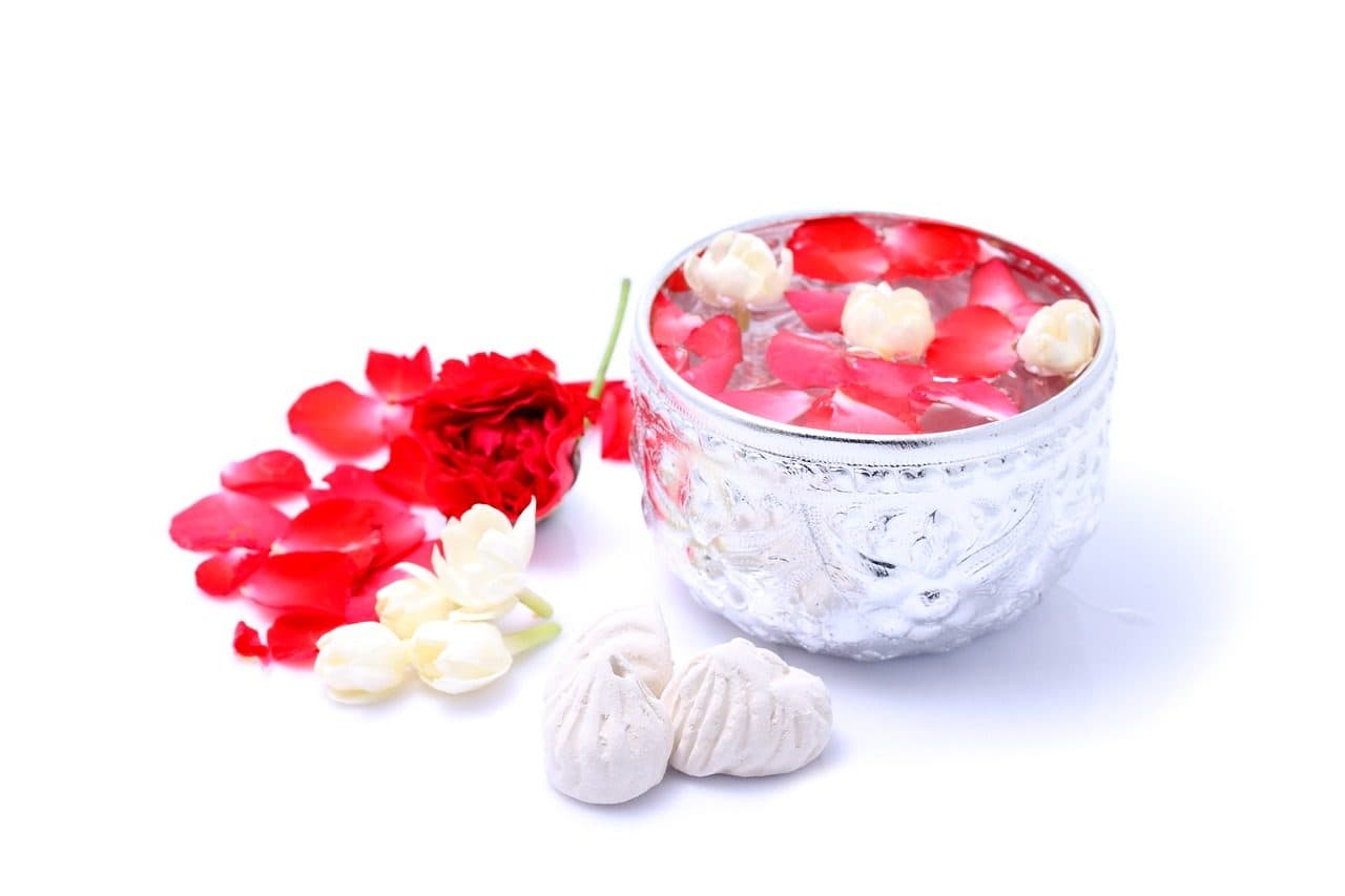 A silver bowl of scented water with jasmine and rose petals, used at Songkran