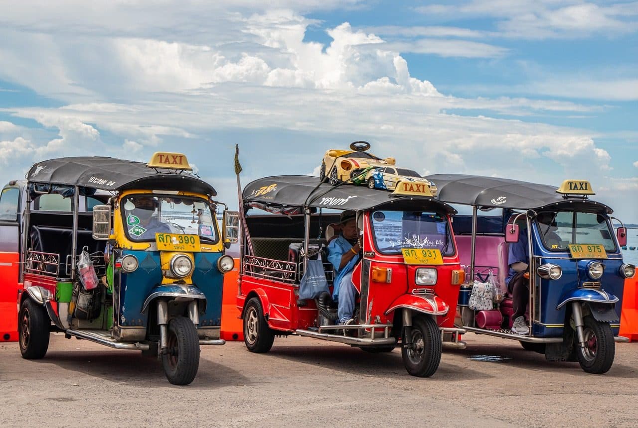 Three brightly coloured tuk-tuks parked in a row