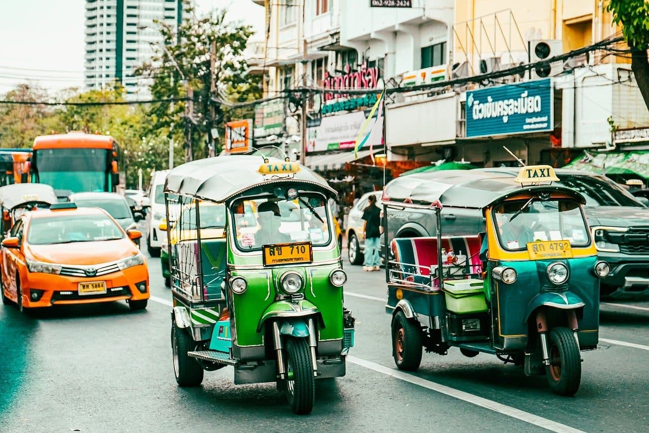 Green tuk-tuks and taxis in Bangkok traffic
